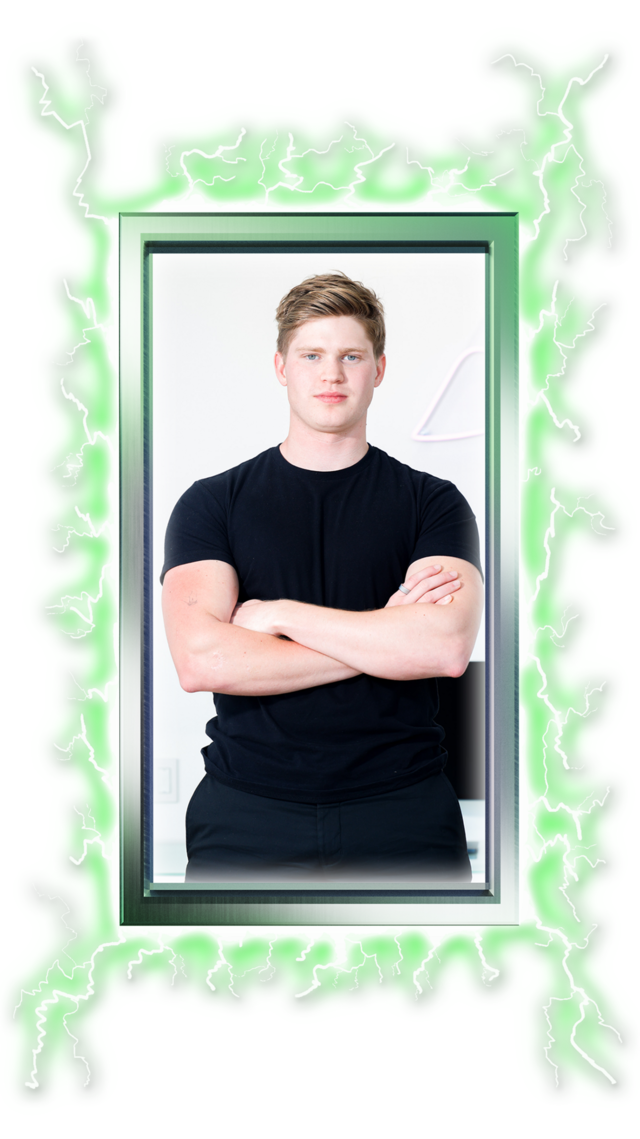 A young man with short light brown hair, wearing a black t-shirt, stands with his arms crossed inside a glowing green, jagged electric frame.